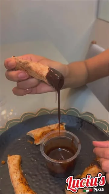 Borda da pizza mergulhada no potinho de creme de avelã